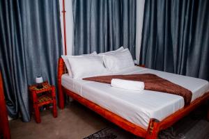 1 dormitorio con 1 cama con cortinas azules en The Hub Train House Apartments, en Zanzíbar