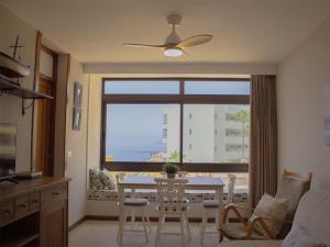 a living room with a table and a large window at Sunset Arena Beach by HelloApartments in Puerto de Santiago