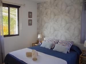 a bedroom with a blue bed with a large wall at Sunset Arena Beach by HelloApartments in Puerto de Santiago +35 photos