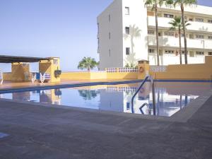 a swimming pool in front of a building at Sunset Arena Beach by HelloApartments in Puerto de Santiago