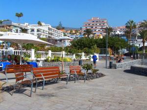 a group of benches and umbrellas on a beach at Sunset Arena Beach by HelloApartments in Puerto de Santiago