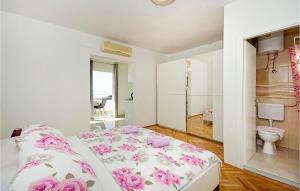 Gorgeous Apartment In Tucepi With House Sea View في توسيبي: غرفة نوم مع سرير مع زهور وردية عليه