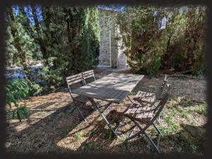 a picnic table and two chairs under a tree at Le Mas des Condamines in Canet