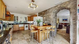 eine Küche mit einem Tisch und einer Steinmauer in der Unterkunft Finest Retreats - Old Barn at Ormidale House in Clachan of Glendaruel