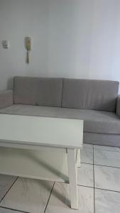 a gray couch with a white table in a room at Single bed space - Al Majaz 2 in Jazīrat al Ḩibāb