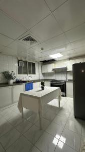a white kitchen with a table in the middle of it at Single bed space - Al Majaz 2 in Jazīrat al Ḩibāb