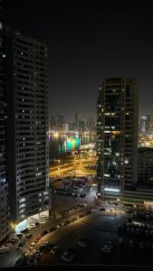 a city at night with cars parked in a parking lot at Single bed space - Al Majaz 2 in Jazīrat al Ḩibāb