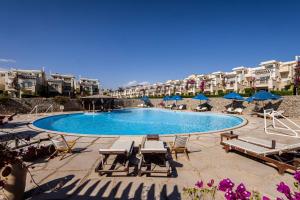 a swimming pool with chairs and umbrellas and buildings at La Cabana Beach Hotel Ain Sokhna in Ain Sokhna