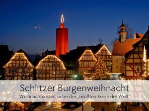 eine beleuchtete Stadt mit Weihnachtsbaum und Gebäuden in der Unterkunft TÜRMERSTUBE - Apartment in der Hinterburg Schlitz - direkt an der "Größten Kerze der Welt" - mit Aufzug, Parkplatz, E-Ladestation & Garten - Hunde willkommen in Schlitz