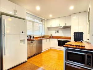 a kitchen with white cabinets and stainless steel appliances at Aloha Bayside 7 bedroom holiday house sleeps 23 Spa Sauna and Garden Views in Highett