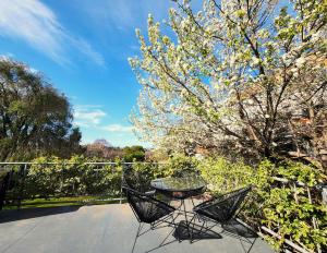 a patio with a table and two chairs and a tree at Aloha Bayside 7 bedroom holiday house sleeps 23 Spa Sauna and Garden Views in Highett