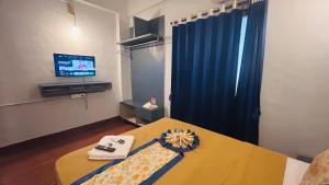 a room with a bed with a television and a table at Hotel Cozy Inn in Kālundri +23 photos