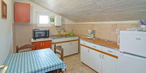 a kitchen with white cabinets and a sink and a table at Antunovic in Veli Lošinj