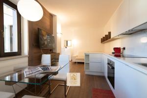 een keuken en een woonkamer met een glazen tafel bij GoldenSuitesItaly Piazza Duomo Luxury Apartment 3 in Trento