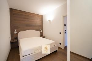 een slaapkamer met een wit bed met een houten hoofdeinde bij GoldenSuitesItaly Piazza Duomo Luxury Apartment 3 in Trento