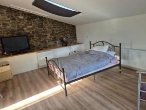 1 dormitorio con 1 cama y TV en una pared de ladrillo en Hawick - House - Sleeps 9 - Hot Tub, en Denholm