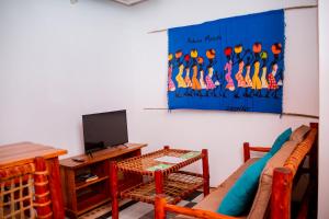 ein Wohnzimmer mit einer Couch, einem Fernseher und einem Tisch in der Unterkunft The Hub Train House Apartments in Zanzibar City