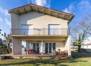 una grande casa bianca con un balcone in cima di Villa Amistad - Chambre Tilleul - centre - parking - jardin - logement partagé - a Mont-de-Marsan