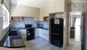 ハラレにあるOlivoakのキッチン(黒い冷蔵庫、白いキャビネット付)