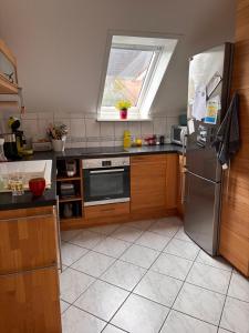 a kitchen with a stainless steel refrigerator and a window at Gut Ellernwurth in Wurster Nordseeküste