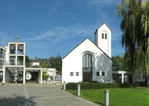a white church with a steeple and a building at Gästehaus Dominikus in Leipzig