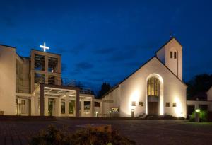 Gästehaus Aurelius Arkenau في Niederdorla: كنيسة مع صليب على جانبها في الليل