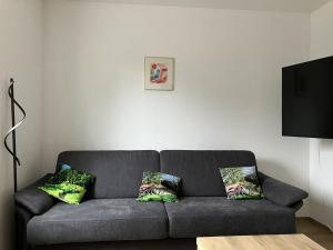 ein Wohnzimmer mit einer grauen Couch mit zwei Kissen in der Unterkunft Ferienhaus Familien-Idyll Bibertalblick in Schnett