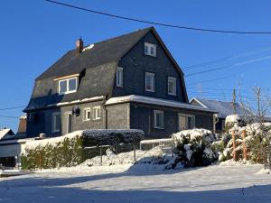ein großes schwarzes Haus mit Schnee davor in der Unterkunft Ferienhaus Familien-Idyll Bibertalblick in Schnett