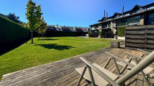 Una terraza de madera con un patio con césped al lado de un edificio. en Morada la Tosa, en Alp