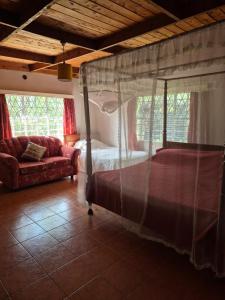 a bedroom with a canopy bed and a couch at Kitengela Farmhouse in Nairobi