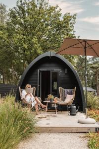 a woman sitting in a chair in front of a black tent at KampinaStaete, hippe cottages midden in natuurgebied de Kampina Oisterwijk in Oisterwijk