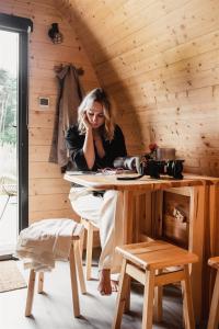 a woman sitting at a table in a wooden room at KampinaStaete, hippe cottages midden in natuurgebied de Kampina Oisterwijk in Oisterwijk