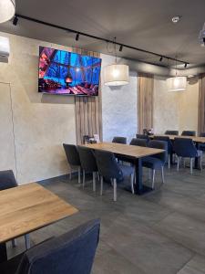 a dining room with tables and chairs and a tv on the wall at Готельний комплекс GАРБУЗ in Zwiahl +59 photos