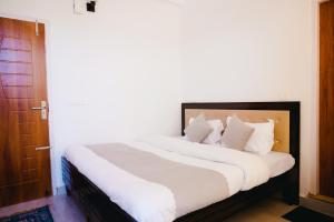 a bedroom with a large bed with white sheets and pillows at Dhananjay home stay in Dharampur