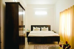 a bedroom with a bed with white sheets and pillows at Dhananjay home stay in Dharampur