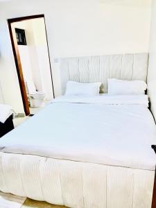Cama blanca grande en habitación con aseo en Terus studio, en Nanyuki
