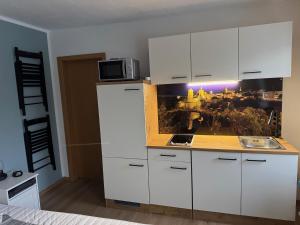 Una cocina con gabinetes blancos y un microondas. en Ferienwohnung Steinstübchen, en Bautzen
