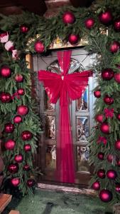 a christmas door with a red bow and decorations at Casa Bucuriei - Plaiul Foii, Zărnești in Zărneşti
