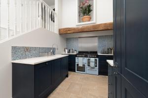 a kitchen with navy blue cabinets and a staircase at Barn Cottage Painswick in Painswick