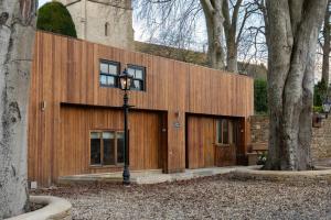 a wooden building with a street light next to two trees at Barn Cottage Painswick in Painswick