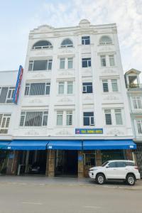 un edificio bianco con un'auto parcheggiata di fronte di Thái Dương Hotel a Tân Hội