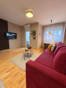 Una sala de estar con un sofá rojo y una mesa. en NAR Royalton Apartment #01, en Niš
