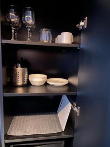 a shelf with plates and glasses and a laptop at SleepWell Apartments Czarna Góra in Sienna
