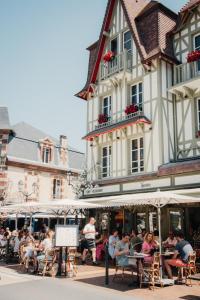 a group of people sitting at tables outside a building at Villa Henriette in Cabourg