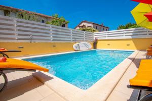 a swimming pool with an umbrella and some chairs at Vila Andja in Banjole,Istrien by Istrabook in Banjole