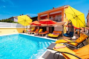 a swimming pool with chairs and umbrellas next to a building at Vila Andja in Banjole,Istrien by Istrabook in Banjole