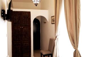um quarto com uma porta, uma cadeira e uma janela em Riad de charme l'Oasis d'Essaouira - Suite Luxe em Essaouira