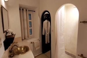 um banheiro com uma pia e uma fantasia na parede em Riad de charme l'Oasis d'Essaouira - Suite Luxe em Essaouira
