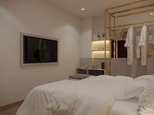 a bedroom with a white bed with a tv on the wall at MAYS Grand Hotel & Spa - Ben Thanh in Ho Chi Minh City