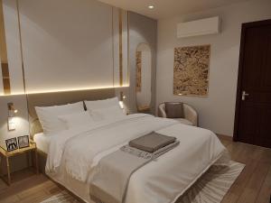 ein Schlafzimmer mit einem großen weißen Bett und einem Stuhl in der Unterkunft MAYS Grand Hotel & Spa - Ben Thanh in Ho-Chi-Minh-Stadt